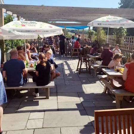 The garden at The Broad Oak on a sunny day, with parasols and full tables