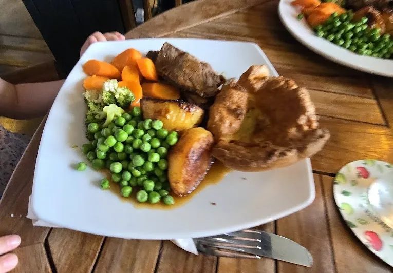 A plated roast dinner with Yorkshire pudding, peas and carrots